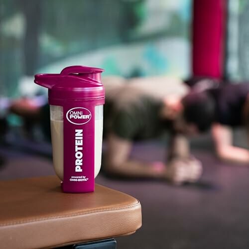 Protein-Shaker im Fitnessstudio mit Personen im Hintergrund